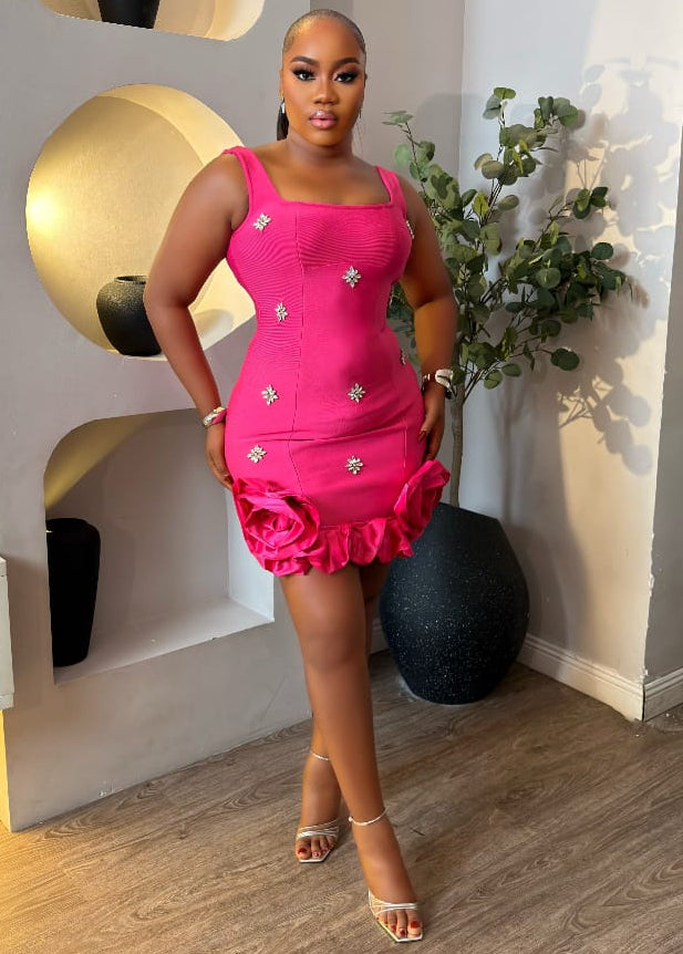 Pink Blush Elowyn Dress by STERA FASHION displayed on a hanger with floral details and flowing fabric.