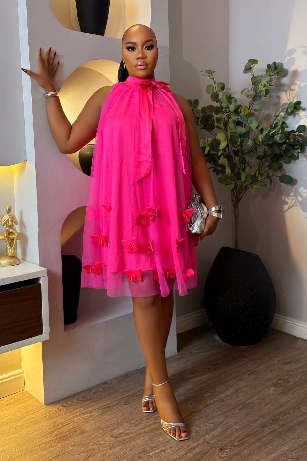 Blush Papillon dress by STERA FASHION displayed on a hanger with floral background, showcasing its flowy fabric and elegant design.